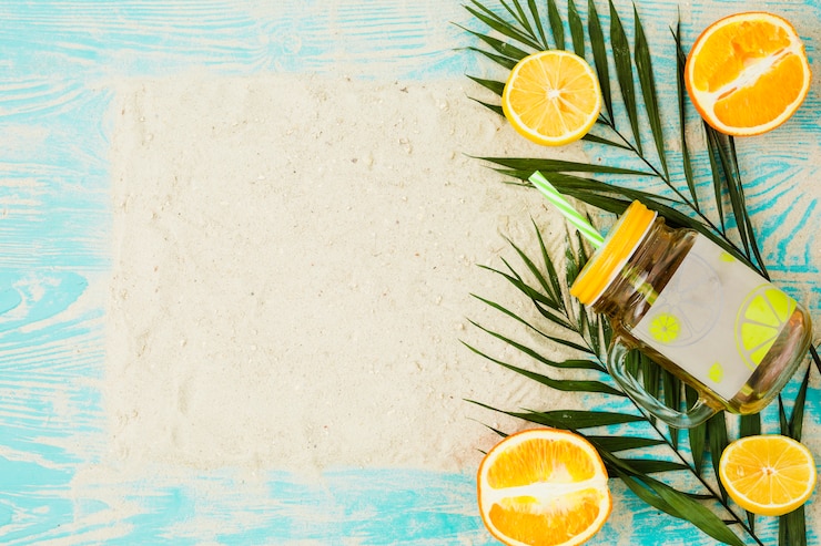Photo gratuit planter des feuilles près d&#39;un verre de boisson et d&#39;oranges avec du sable à bord