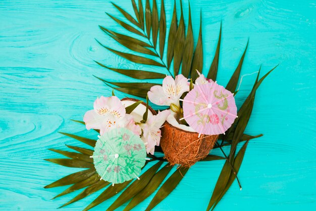 Plantez des feuilles et des noix de coco près des fleurs et des parapluies décoratifs
