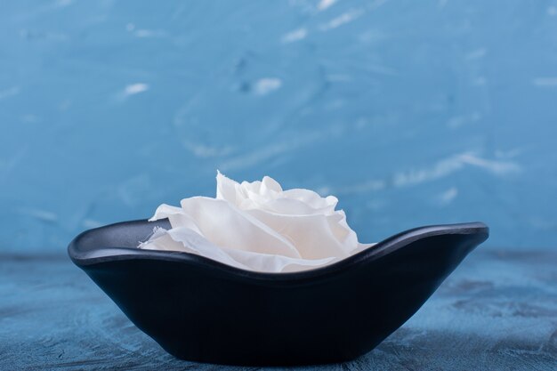 Une plaque noire avec une fleur rose blanche sur bleu.