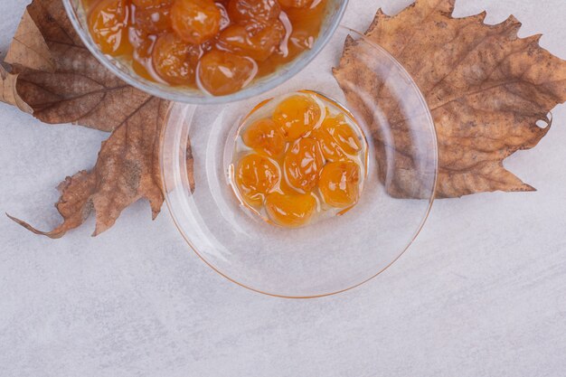 Une plaque de verre de confiture sur une surface blanche