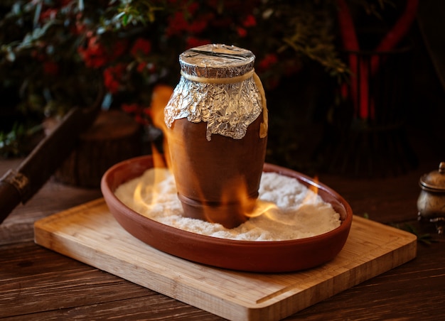 Plat azerbaïdjanais cuit dans un pot en poterie recouvert de papier d'aluminium en feu