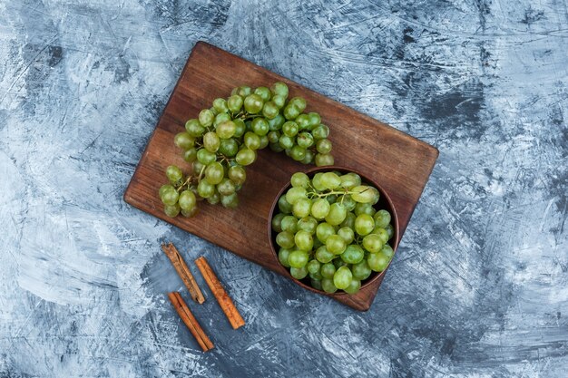 Plat poser bol de raisins sur une planche à découper avec de la cannelle sur fond de marbre bleu foncé. horizontal