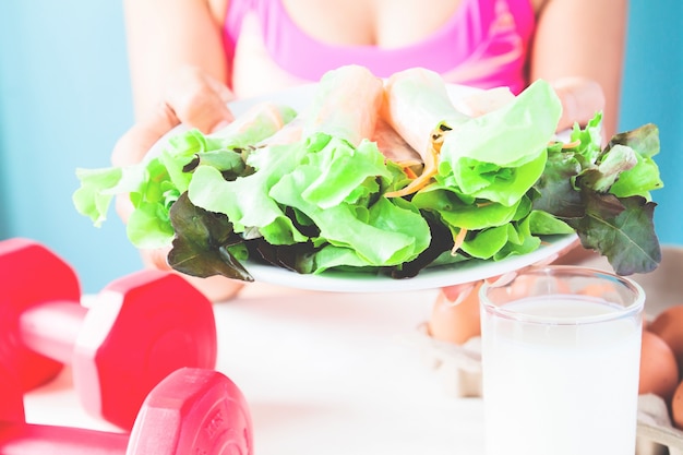 Plat de salade de fitness avec lait, oeufs et haltères sur table, concept de mode de vie sain