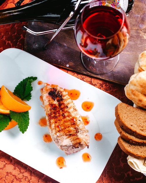 Photo gratuite un plat de viande vue de dessus en tranches avec des feuilles vertes et des citrons en tranches sur le plancher en bois brun