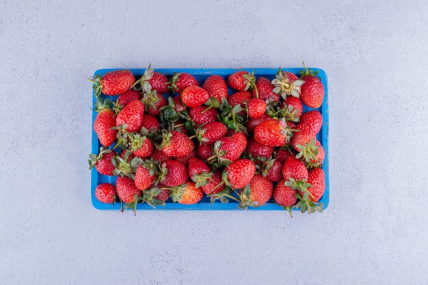 Plateau bleu avec une portion de fraises sur fond de marbre. photo de haute qualité