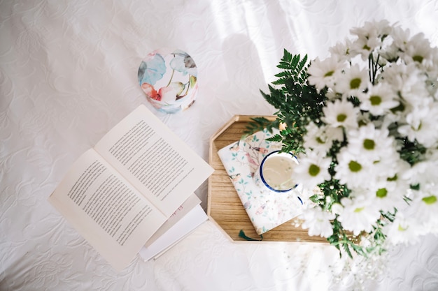 Plateau avec bouquet près du livre ouvert