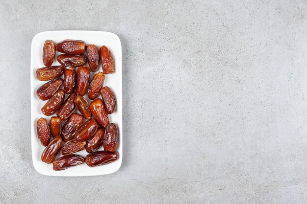 Un plateau de dattes appétissantes sur fond de marbre. Photo de haute qualité