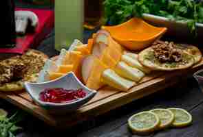 Photo gratuite plateau de fromages avec variations de fromages, craquelins, noix et confiture de fraises