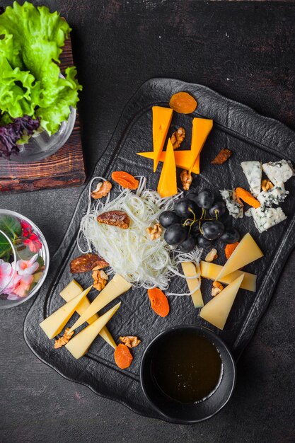 Plateau de fromages vue de dessus avec raisins et noix et miel dans le bac