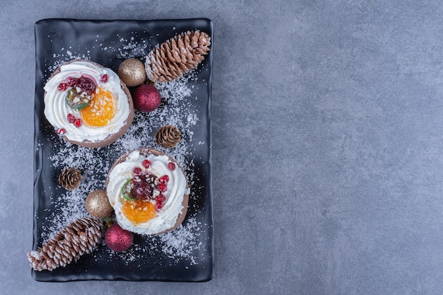 Photo gratuite un plateau noir avec des pâtisseries crémeuses et des bonbons à la gelée sucrée