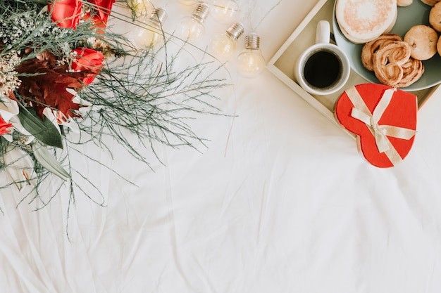 Plateau avec petit-déjeuner et cadeau près du bouquet