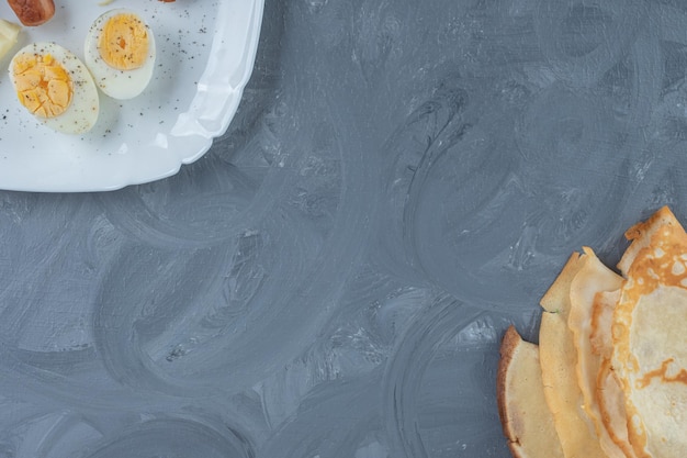 Plateau de petit-déjeuner et crêpes alignés sur une table en marbre.