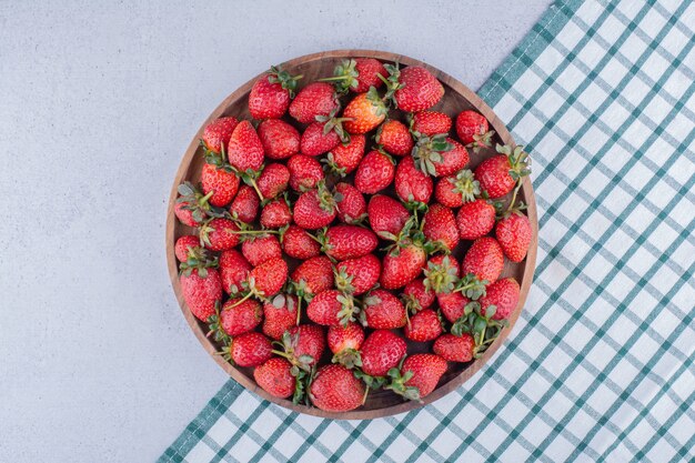 Plateau plein de fraises sur fond de marbre.