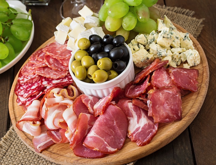 Photo gratuit plateau de restauration antipasto avec bacon, saccadé, salami, fromage et raisins sur une table en bois