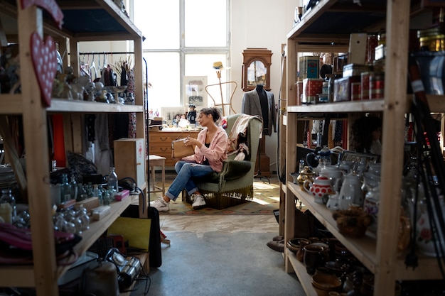 Photo gratuite plein coup femme assise dans un magasin d'aubaines