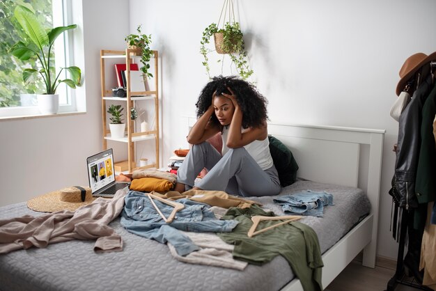 Plein coup femme assise dans son lit avec des vêtements