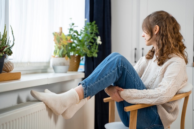 Plein coup femme assise près du radiateur