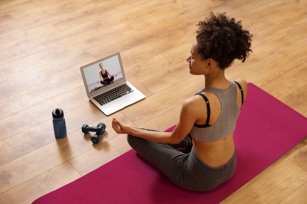 Photo gratuite plein coup femme assise sur un tapis de yoga