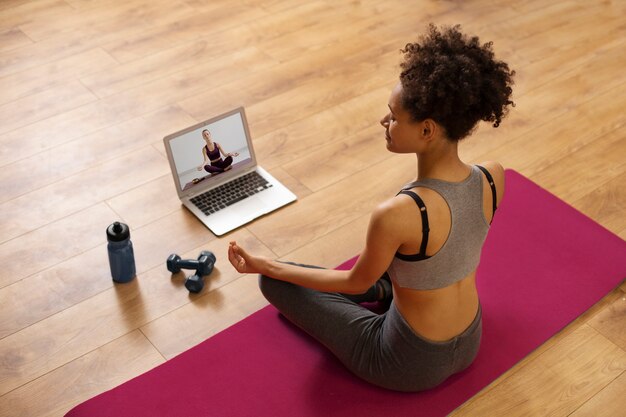 Plein coup femme assise sur un tapis de yoga