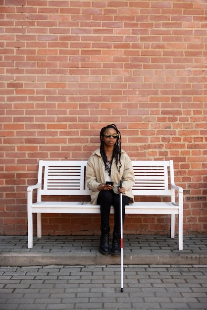 Photo gratuite plein coup femme aveugle assise sur un banc