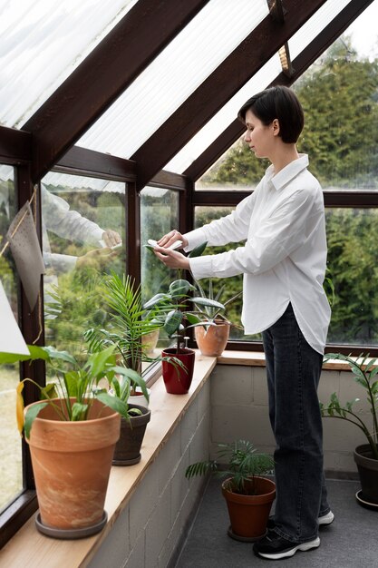 Plein coup femme essuyant la feuille de la plante