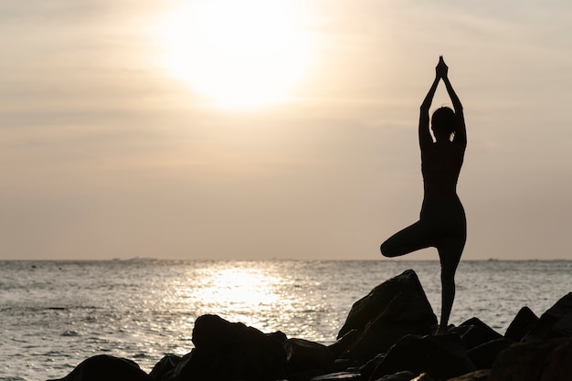Plein coup femme faisant du yoga au coucher du soleil