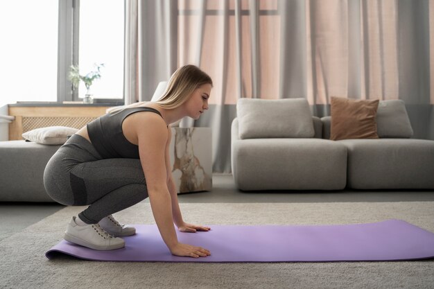 Plein coup femme faisant de l'exercice sur un tapis