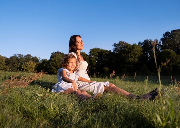 Photo gratuite plein coup femme et fille assise sur l'herbe