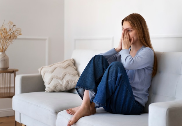 Plein coup femme inquiète assise sur un canapé