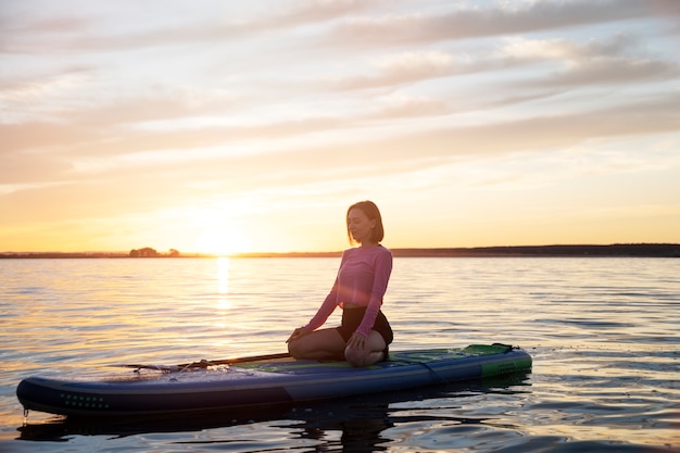Photo gratuite plein coup femme méditant sur paddleboard