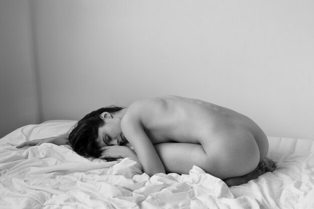 Plein coup femme posant nue dans son lit