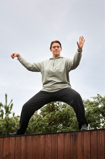 Plein coup femme pratiquant le tai chi à l'extérieur