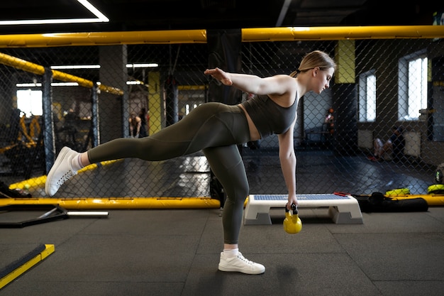 Plein coup femme s'entraînant avec kettlebell au gymnase