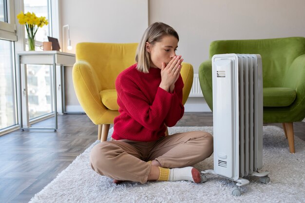 Plein coup femme se réchauffer près du radiateur