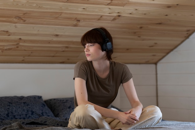 Plein coup femme triste portant des écouteurs à la maison