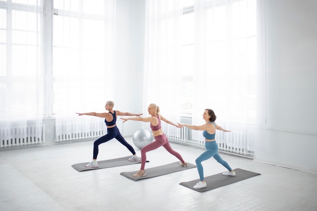 Photo gratuite plein coup de femmes sur un tapis de yoga