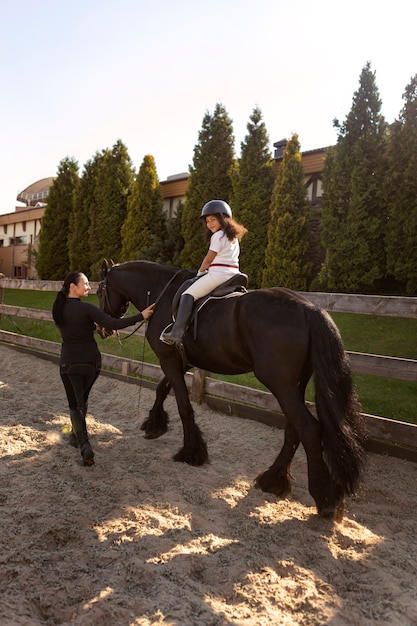 Photo gratuite plein coup fille apprenant à monter à cheval