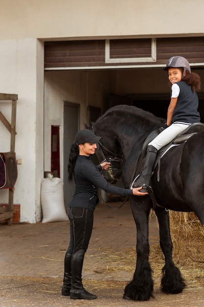 Plein coup fille apprenant à monter à cheval