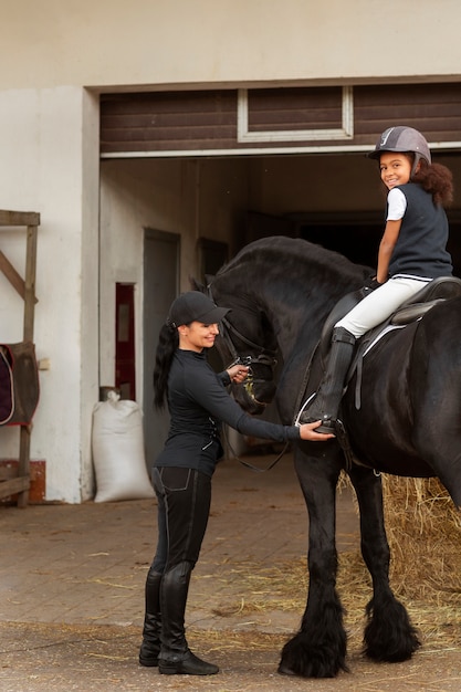 Photo gratuite plein coup fille apprenant à monter à cheval