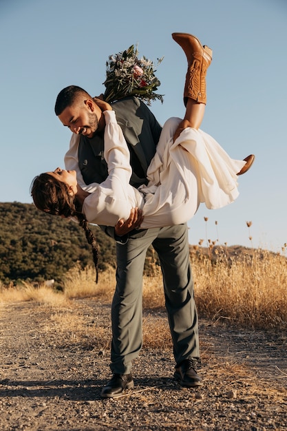 Photo gratuite plein coup heureux marié tenant la mariée