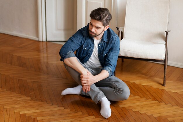 Plein coup homme assis sur le plancher