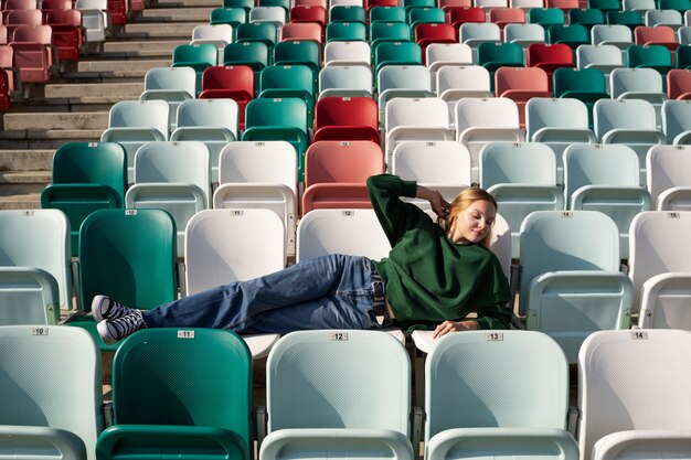 Plein coup jeune femme assise sur les tribunes