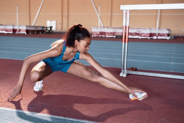 Plein coup jeune femme qui s'étend de la jambe au gymnase