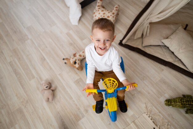 Plein coup petit enfant avec tricycle à la maison