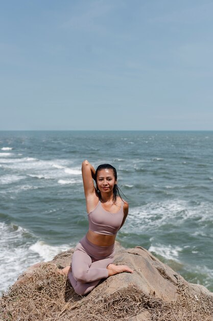 Plein coup smiley femme faisant du yoga dans la nature