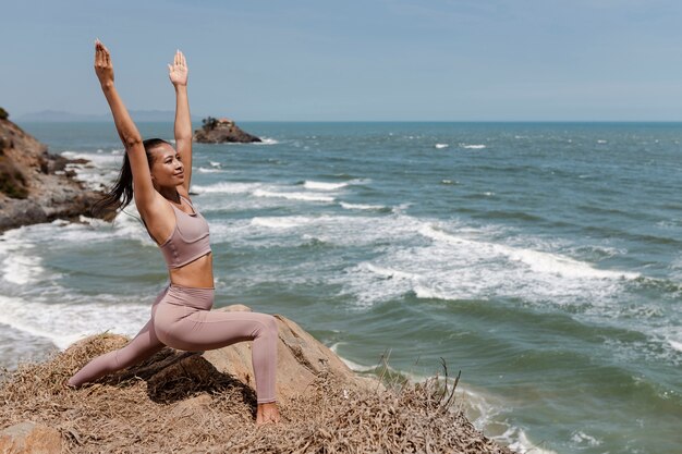 Plein coup smiley femme faisant du yoga dans la nature