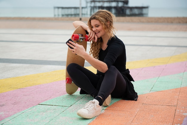 Plein coup smiley femme tenant une planche à roulettes