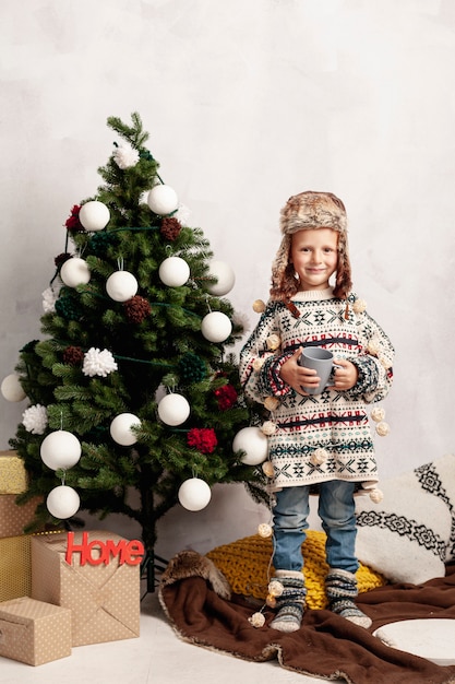 Photo gratuite plein smiley kid près de l'arbre de noël