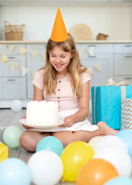 Pleine fille souriante tenant un gâteau