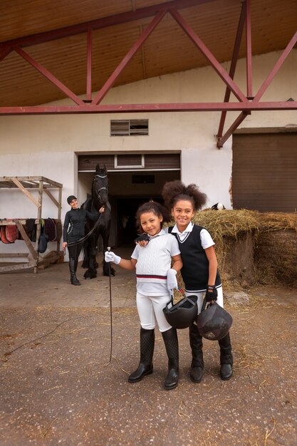 Pleine photo d'enfants apprenant à monter à cheval